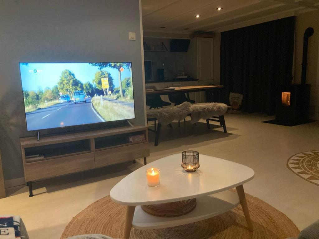 een woonkamer met een televisie en een tafel met kaarsen bij Zeebries in Makkum