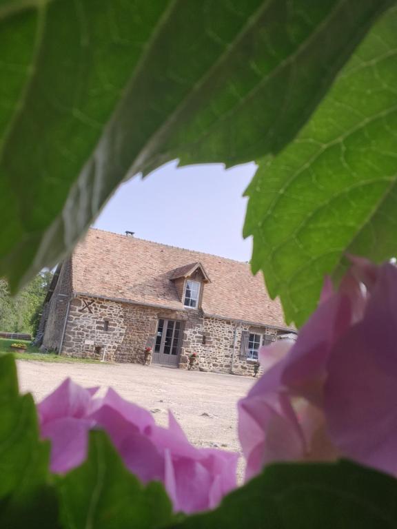 un edificio de piedra con flores delante en Les naturelles, en Saint-Aubin-de-Locquenay
