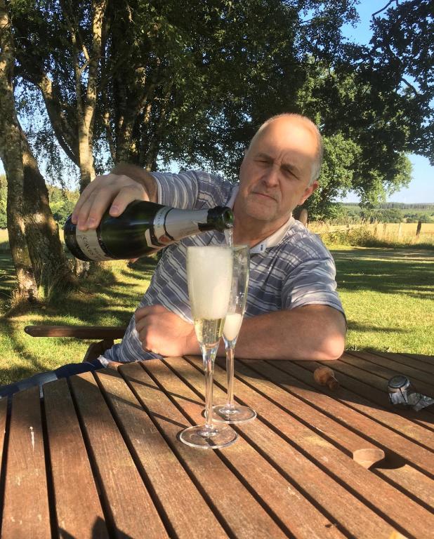 a man pouring a glass of wine on a picnic table at Le Buisson B&amp;B in Gouvy