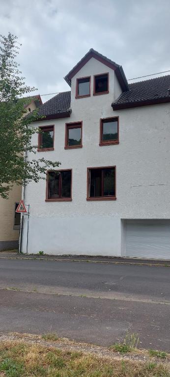 a white building with red windows on a street at Ferienhaus Kastanienblick in Moselkern