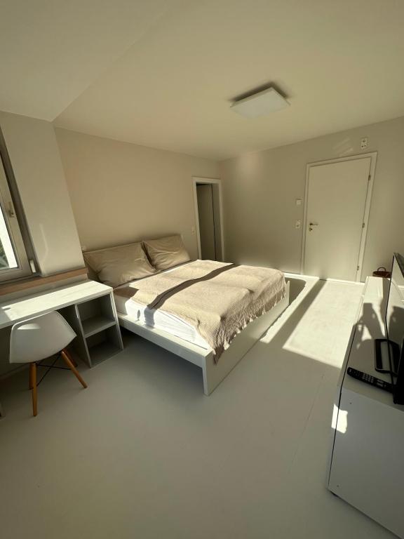 a white bedroom with a bed and a desk at Casa Móre BEIGE in Niederalm