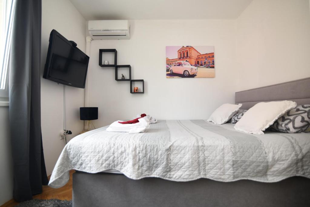 1 dormitorio con 1 cama blanca y TV en GretaNola studio in Zagreb, parking, self check-in, en Zagreb