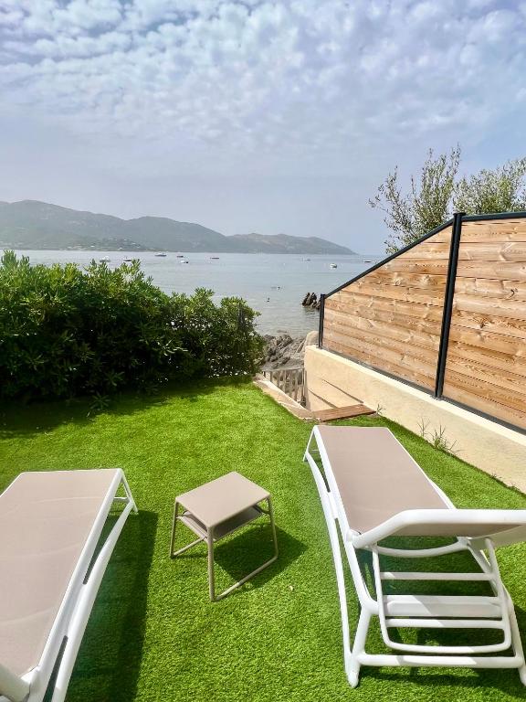 une pelouse avec deux chaises, une table et un banc dans l'établissement Appartement 2-4 pers, ACCES DIRECT MER, à Casaglione
