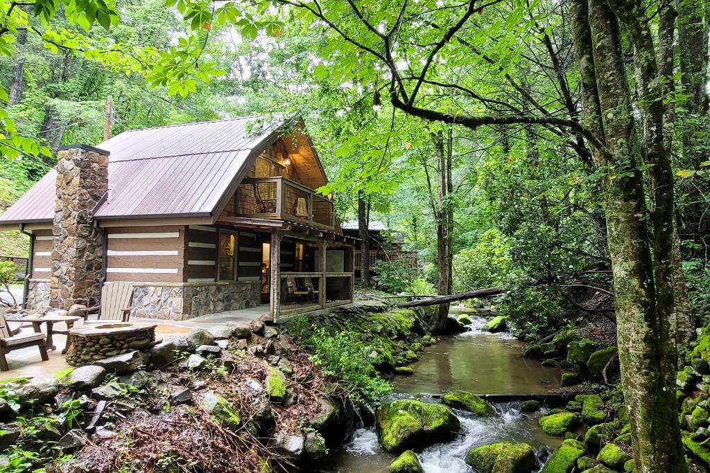 a log cabin in the woods next to a stream at Up the Creek in Gatlinburg