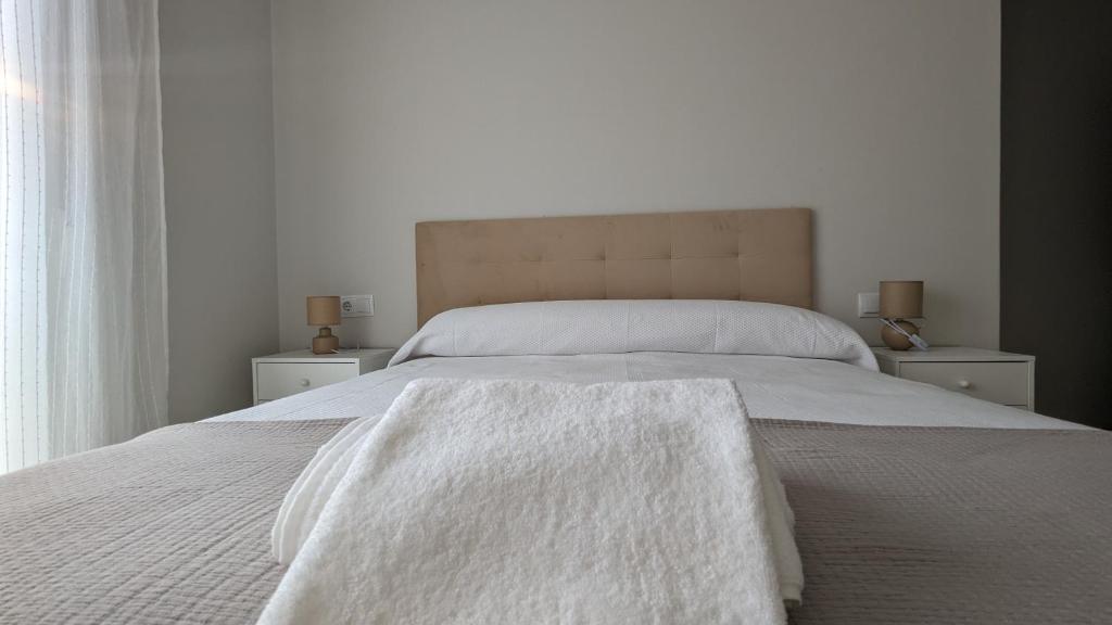 ein Schlafzimmer mit einem Bett mit weißen Decken und einem Fenster in der Unterkunft Playa de Vilariño in Cangas