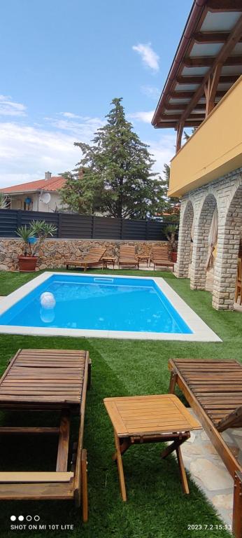 una piscina con 2 mesas y 2 bancos en Holiday house with heated pool Vugica, en Polje