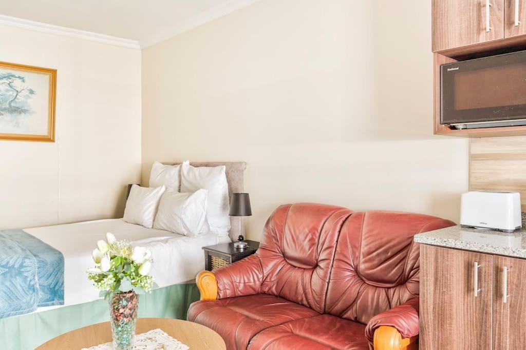 a living room with a leather chair and a bed at Goodwood Oasis Free WiFi-Parking 2 in Cape Town