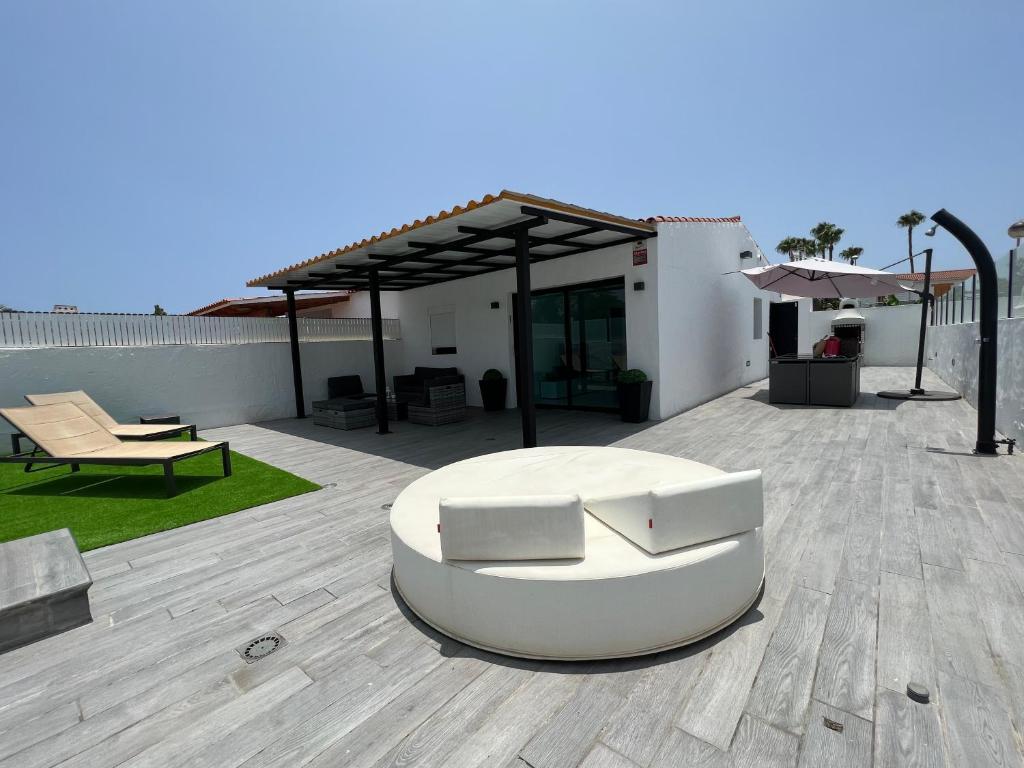 a patio with a white couch and a pavilion at Agradable Bungalow con Piscina in Playa del Ingles