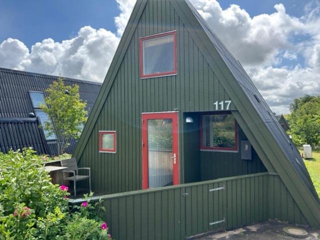 a green house with a red door and windows at Nice holiday home in beautiful resort in Farsø