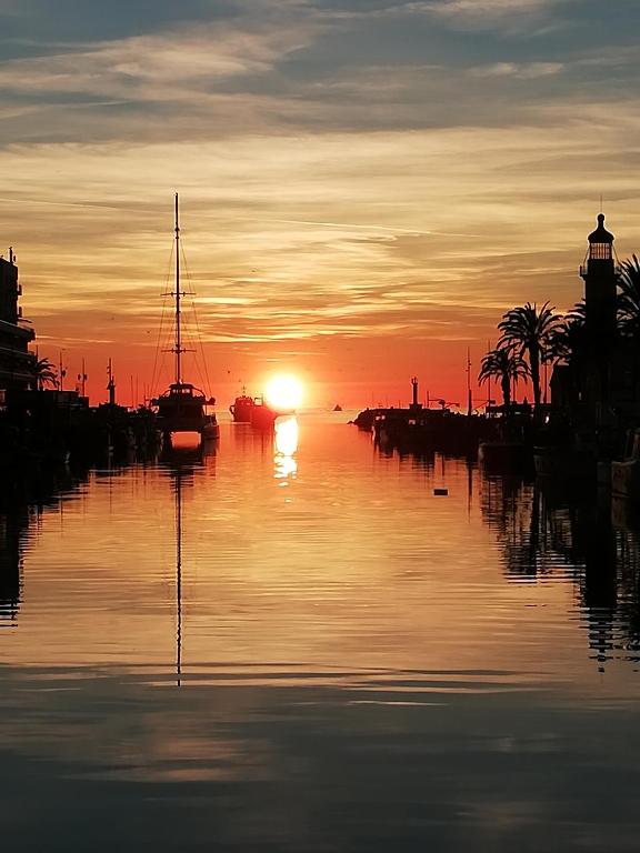 un coucher de soleil sur une étendue d'eau avec un bateau dans l'établissement Grau du roi, au Grau-du-Roi