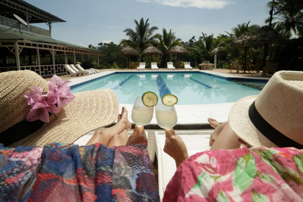 two women sitting in chairs next to a swimming pool at Misahualli Amazon Lodge in Puerto Misahuallí