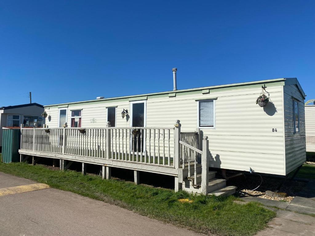 a white mobile home with a porch and a fence at Seaview - 84 - Ingoldmells in Ingoldmells
