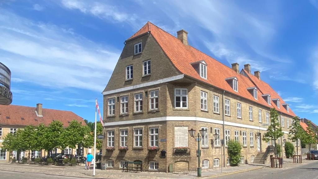 ein großes Backsteingebäude mit orangefarbenem Dach in der Unterkunft Brødremenighedens Hotel in Christiansfeld