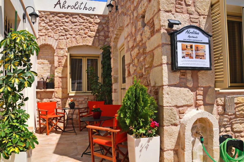 un bâtiment en pierre avec des chaises et une table sur une terrasse dans l'établissement Akrolithos Apartments, à Ierápetra