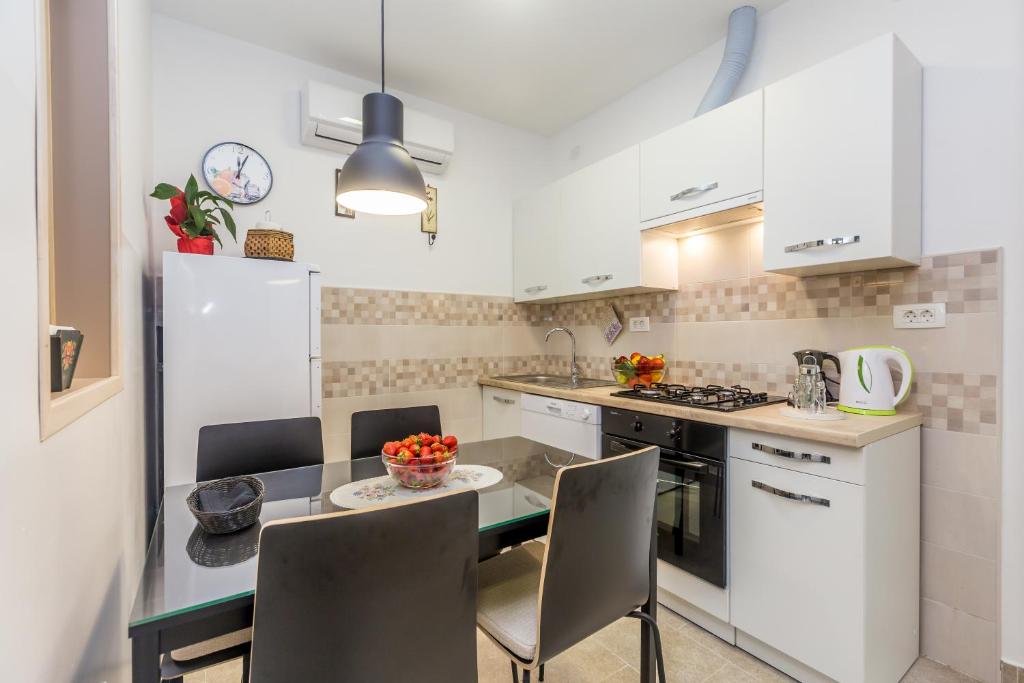 una cocina con armarios blancos y una mesa con sillas. en Kozala Apartment, en Rijeka