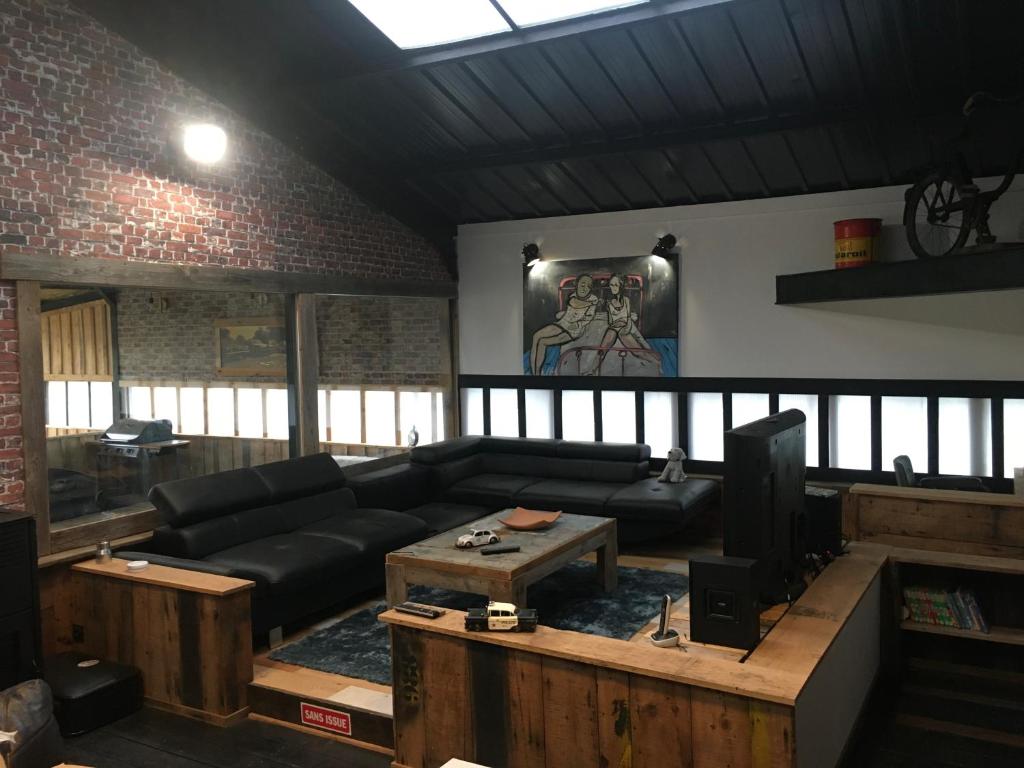 a living room with a black couch and a table at Magnifique loft atypique proche gare et bord de rivière in Le Mans