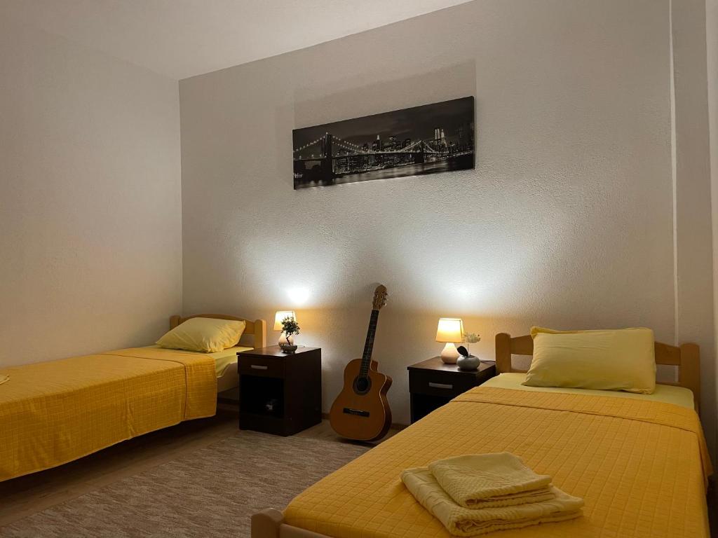 Cette chambre comprend 2 lits et une guitare sur le mur. dans l'établissement Old Town Oasis, à Podgorica