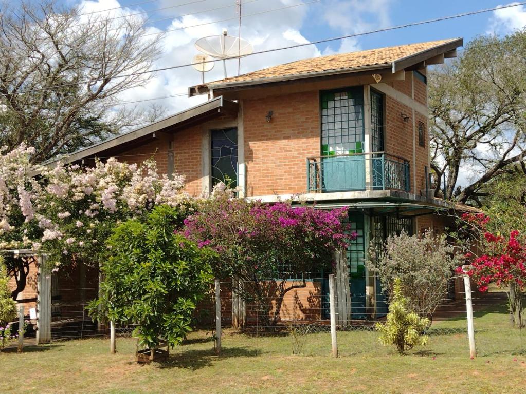 a house with a balcony and flowers in front of it at Analândia: para dormir e sonhar in Analândia