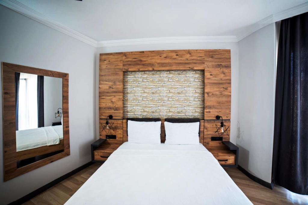 1 dormitorio con 1 cama grande y espejo en İmroz Adali's Butik Otel, en Gokceada Town
