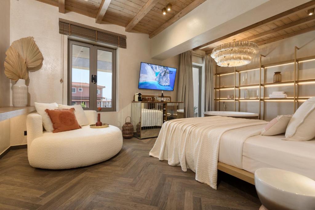 a bedroom with two beds and a chair and a tv at Agave Boutique Hotel in Laganas