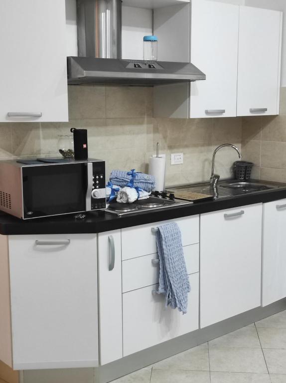 a kitchen with white cabinets and a microwave at Casa Lore in Livorno