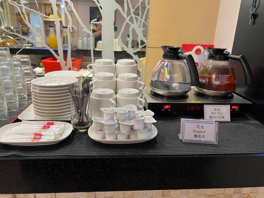 a table with white cups and plates and coffee makers at Link World Hotel in Taipei