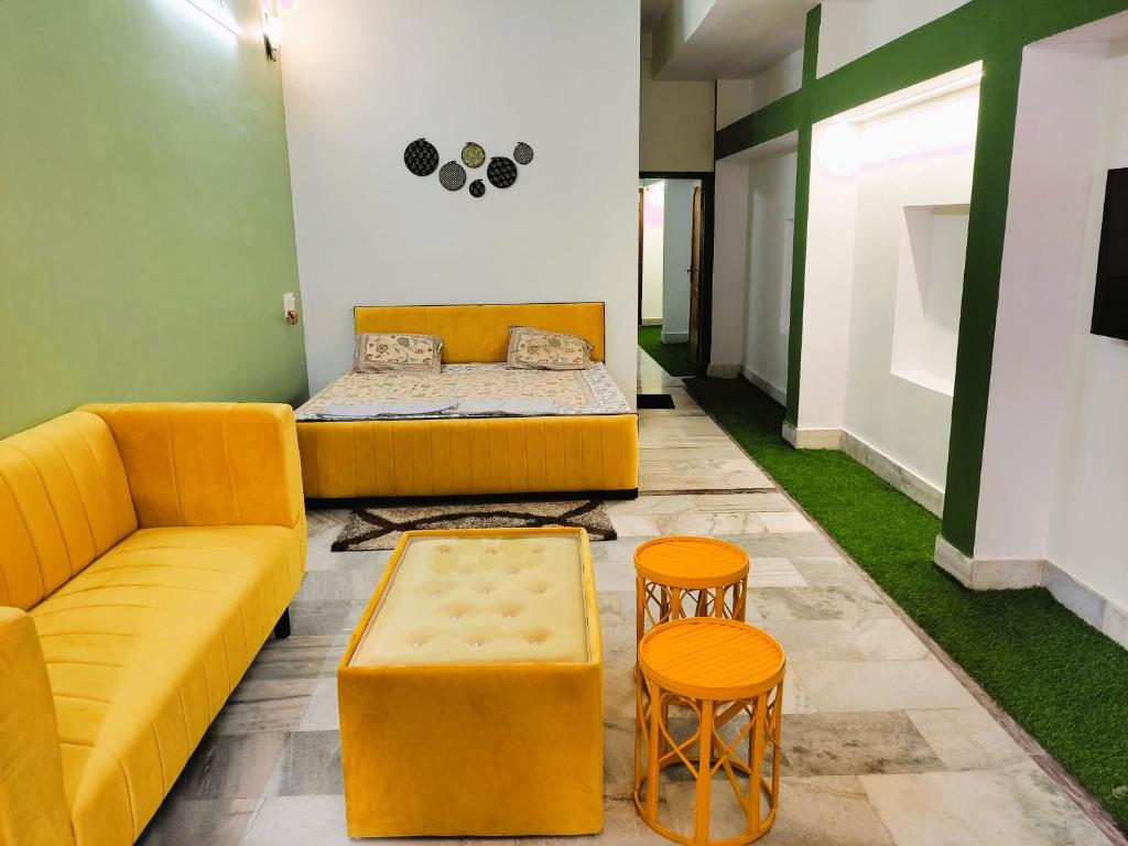 a room with a couch and a bed and two stools at Yellow Homestay - Modern 2BHK AC stay in Jabalpur