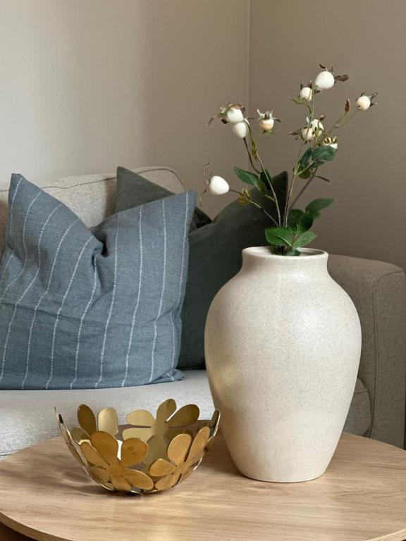 eine weiße Vase auf einem Tisch mit einer Schüssel Blumen in der Unterkunft Knøsesmauet Apartment in Bergen