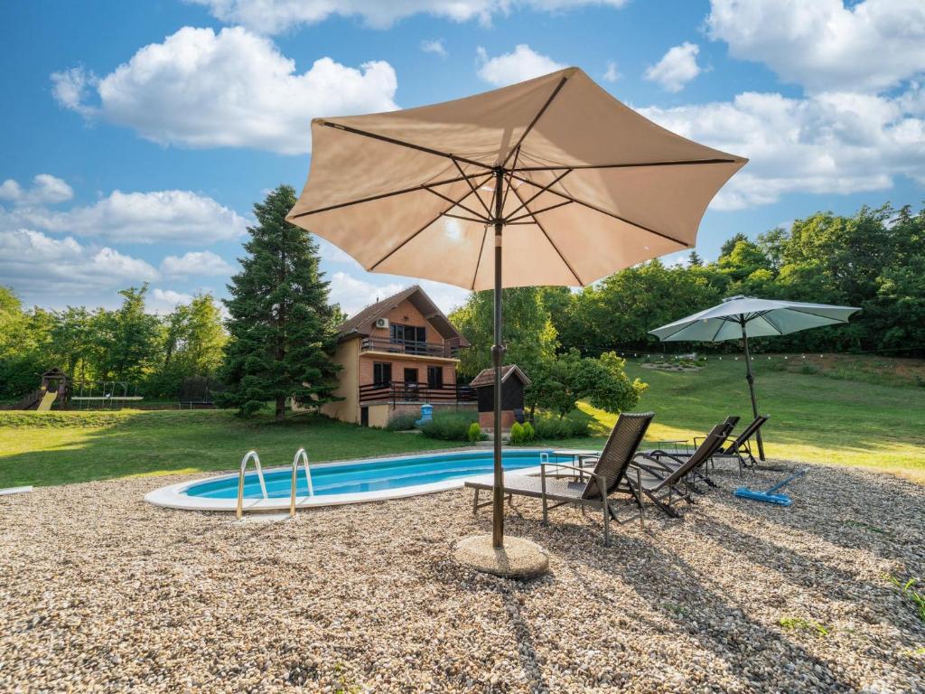 a large umbrella and two chairs and a pool at Fruska Pool House in Sremska Kamenica