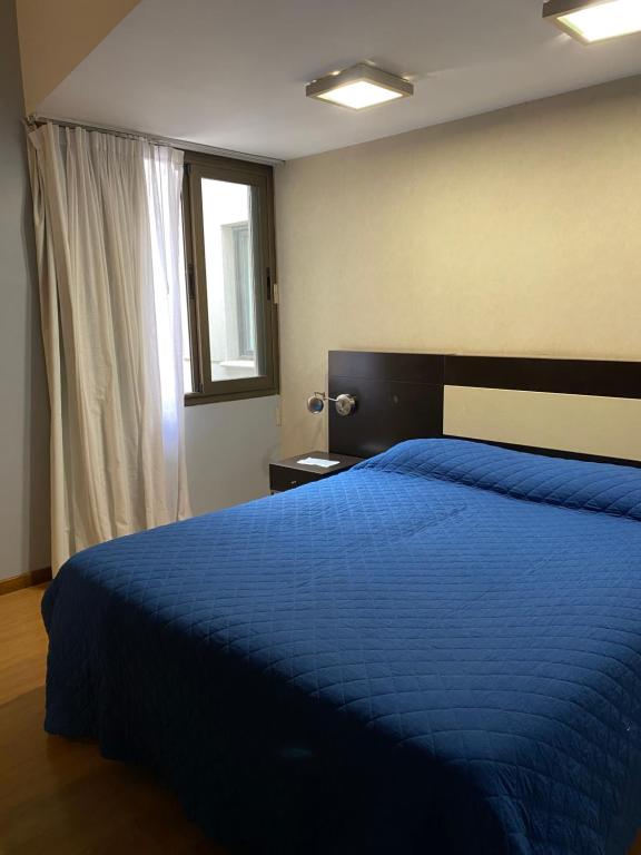 a bedroom with a blue bed and a window at Urban I - Cómodo monoambiente en pleno centro in San Juan