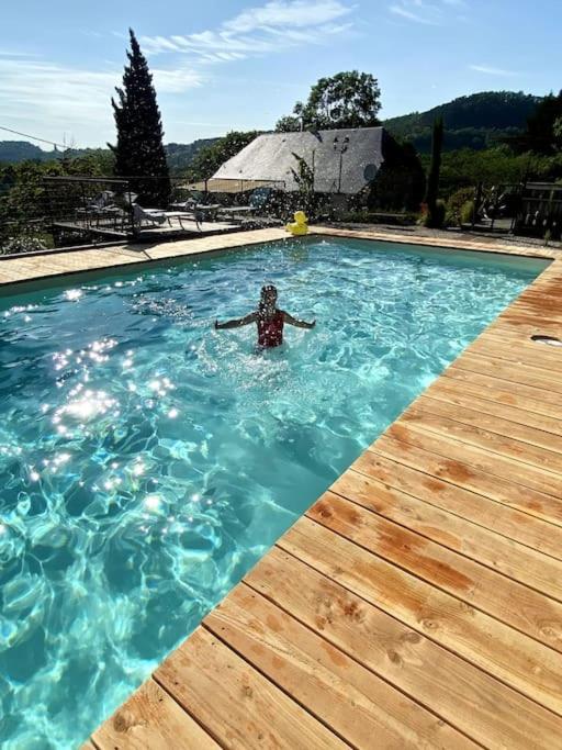 une personne se baignant dans une piscine dans l'établissement Maison Bons Jours. Grange traditionelle avec piscine, à Perpezac-le-Blanc