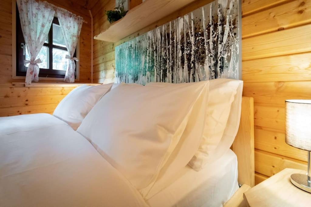 a bedroom with a white bed in a wooden room at Forest Amerika-Bungalovi Milica in Vrbovsko