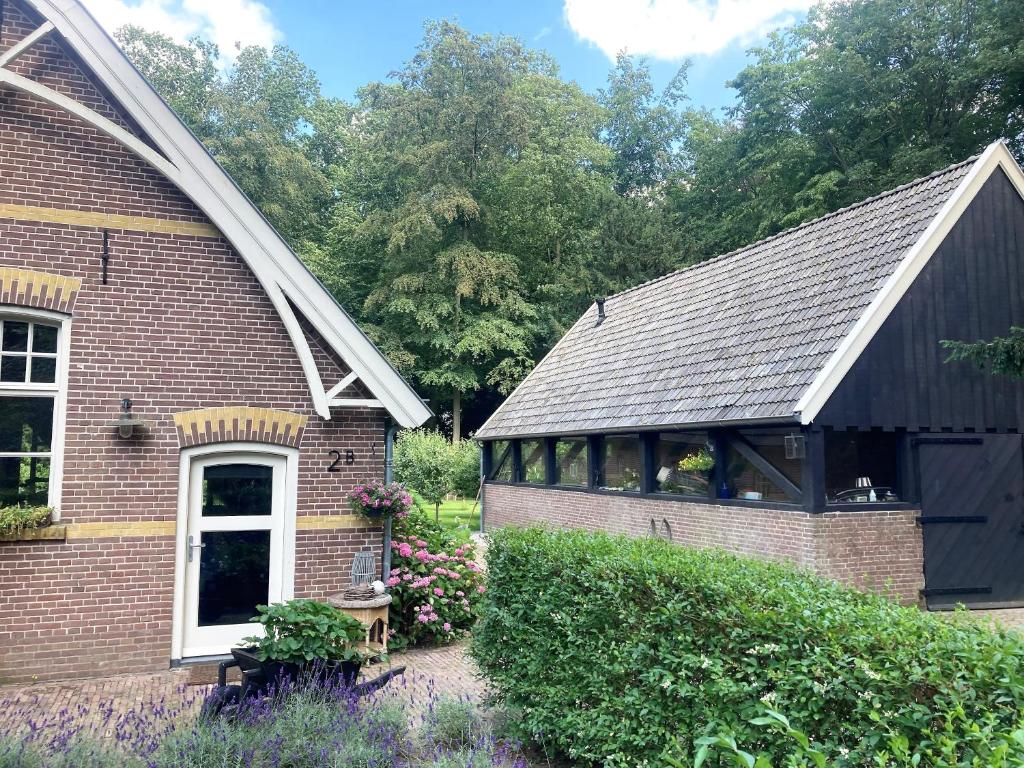a brick house with a black roof and a window at Landgoedhuisje de Blije Uil in Zwolle