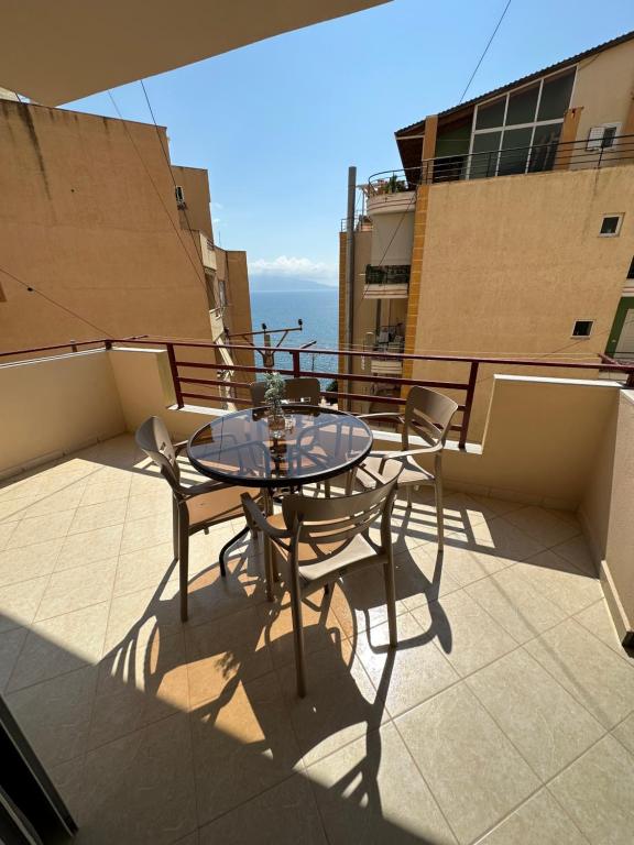 een tafel en stoelen op een balkon met uitzicht op de oceaan bij Arkadia Saranda in Sarandë