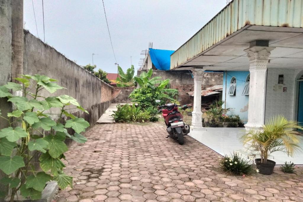 棉蘭的住宿－SPOT ON 92697 Ani Nur Homestay Syariah，停在建筑物外的摩托车