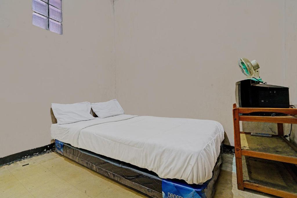 uma pequena cama num quarto com uma colcha branca em OYO Life 92709 Kost Teras Cikapundung Syariah em Bandung