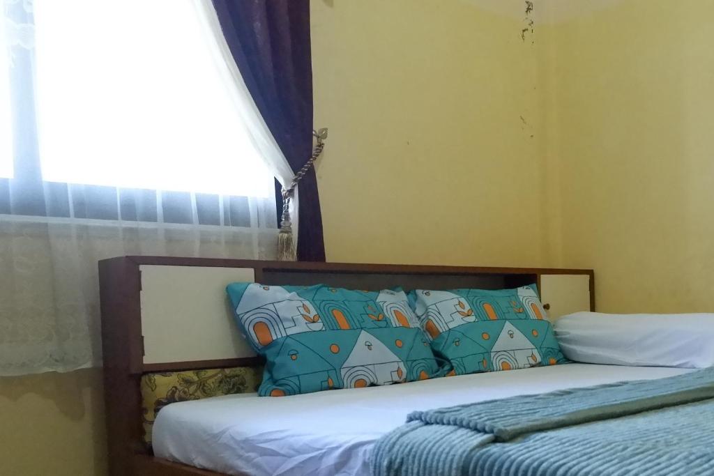 Un dormitorio con una cama con almohadas azules y una ventana en SPOT ON 92760 Global Media Homestay Syariah, en Semarang