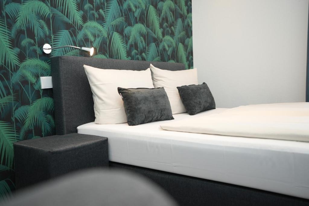 a white bed with two pillows and a green wallpaper at Hotel Attaché an der Messe in Frankfurt&#47;Main