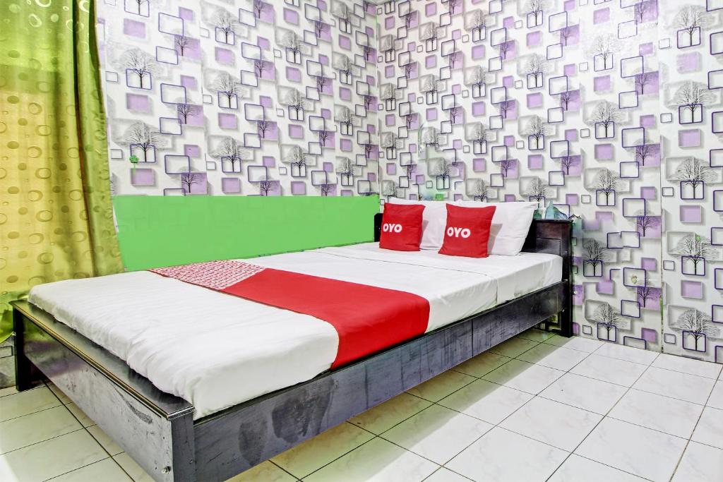um quarto com uma cama com duas almofadas vermelhas em OYO 92759 Penginapan Piji Kembar em Karanganyar