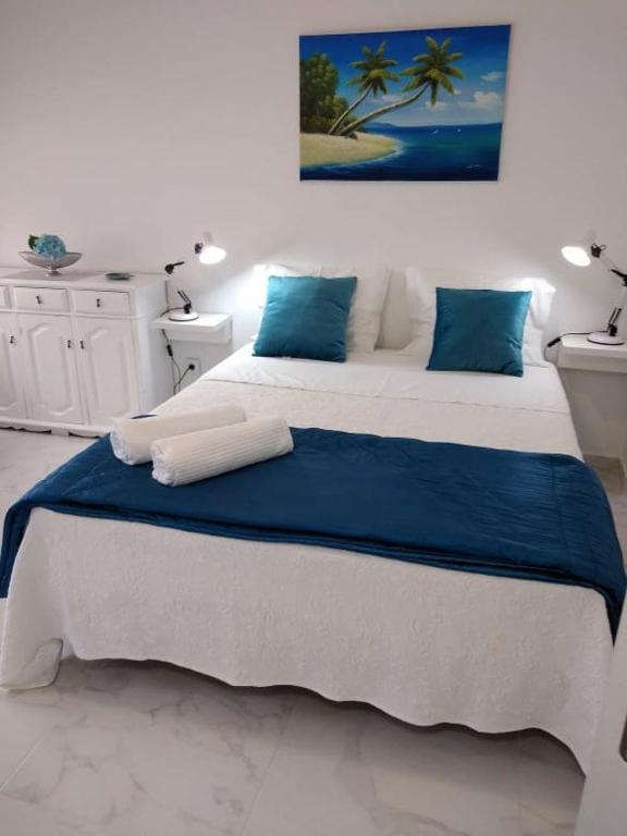 a white bedroom with a large bed with blue pillows at JB House in Nazaré