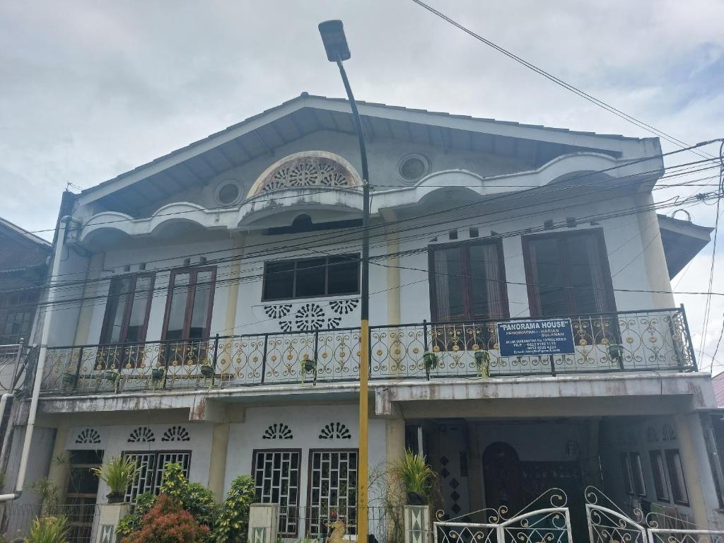 a white building with a balcony on a street at SPOT ON 92776 Panorama House in Tomohon