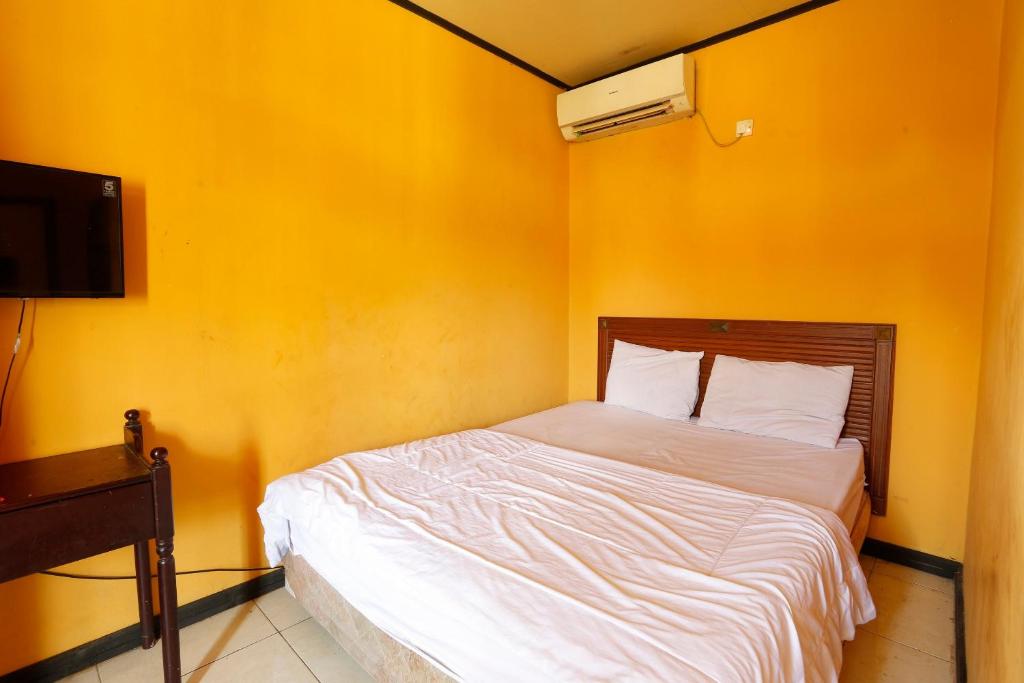 a bed in a room with a yellow wall at SPOT ON 92782 Rumah Kost Kita Tarakan in Tarakan