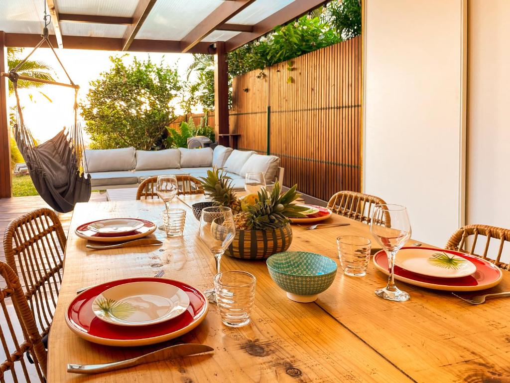 una mesa de madera con platos y copas de vino. en Appartement T2 de vacances St Gilles les Bains   , en Saint-Gilles-les-Bains