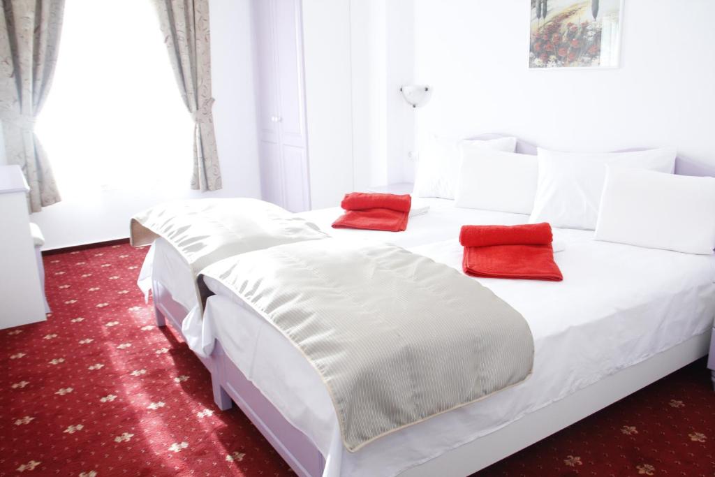 Una cama blanca con dos almohadas rojas. en Hotel Exclusiv en Timisoara