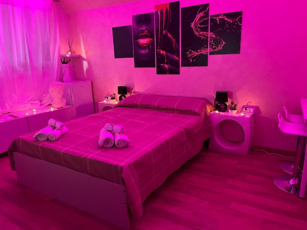 een roze slaapkamer met twee roze kattenschoenen op een bed bij Sergio’s home in Vittoria
