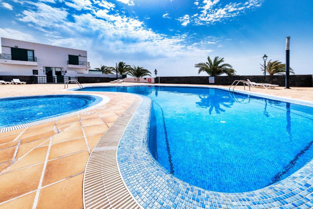 a large swimming pool with blue water at Casa Costa Esmeralda-shared pool in Costa Teguise