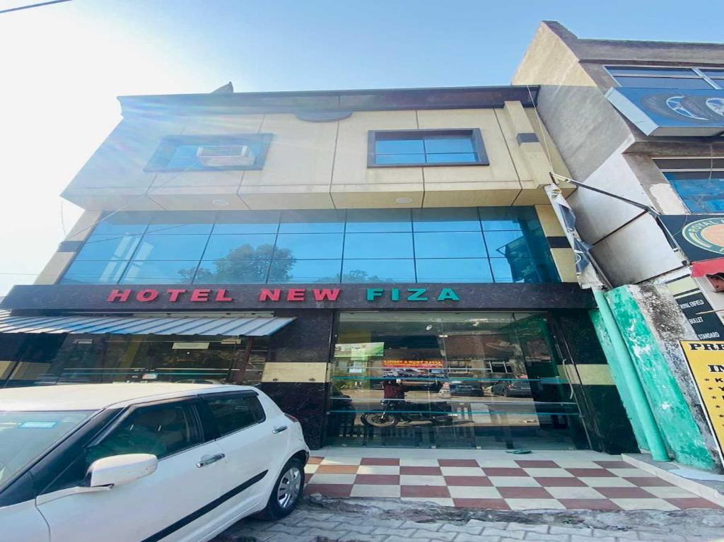 OYO Flagship 12976 Hotel New Fiza في جامو: سيارة فان بيضاء متوقفة أمام الفندق بيتزا جديدة