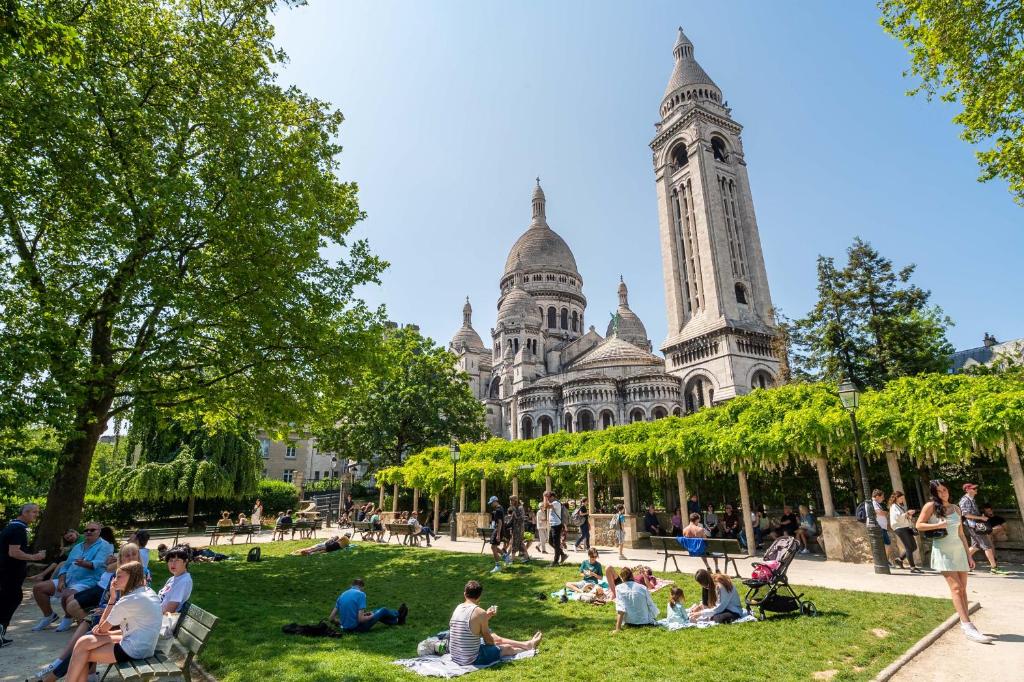 people sitting on the grass in front of a building at In front of The Sacre Cœur - 2 bedrooms with elevator in Paris