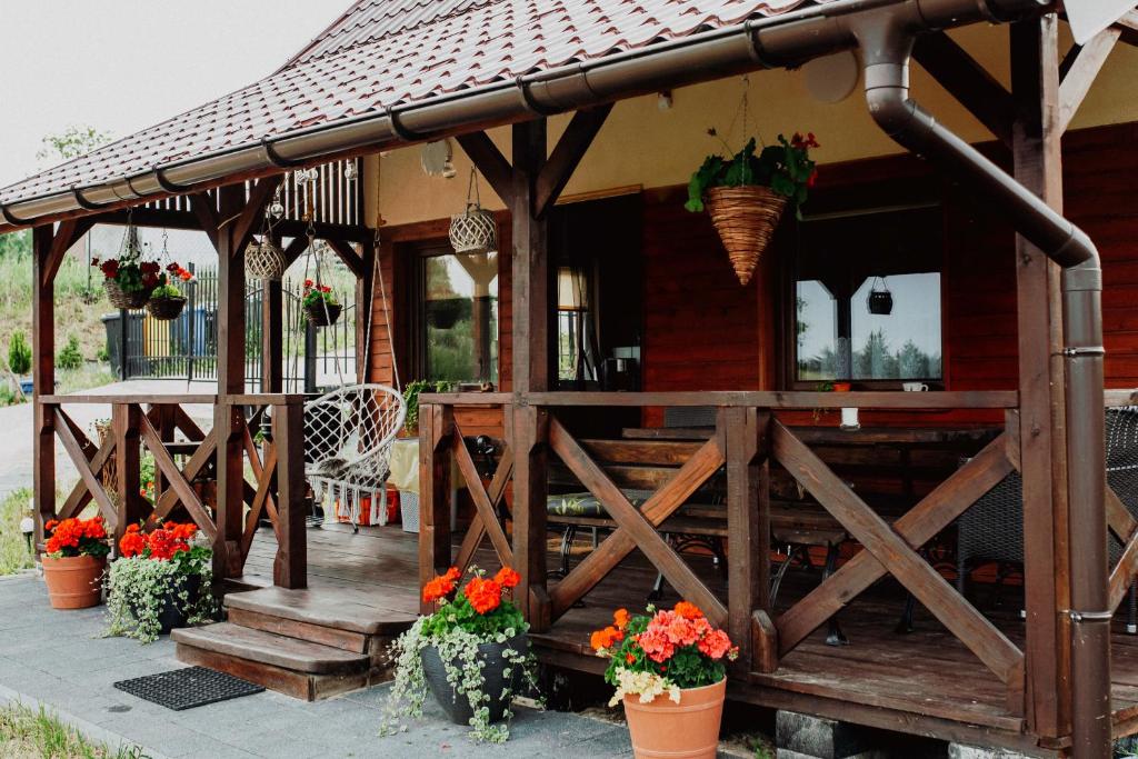 a house with a wooden porch with flowers in pots at Domek na skarpie in Szczybały Giżyckie