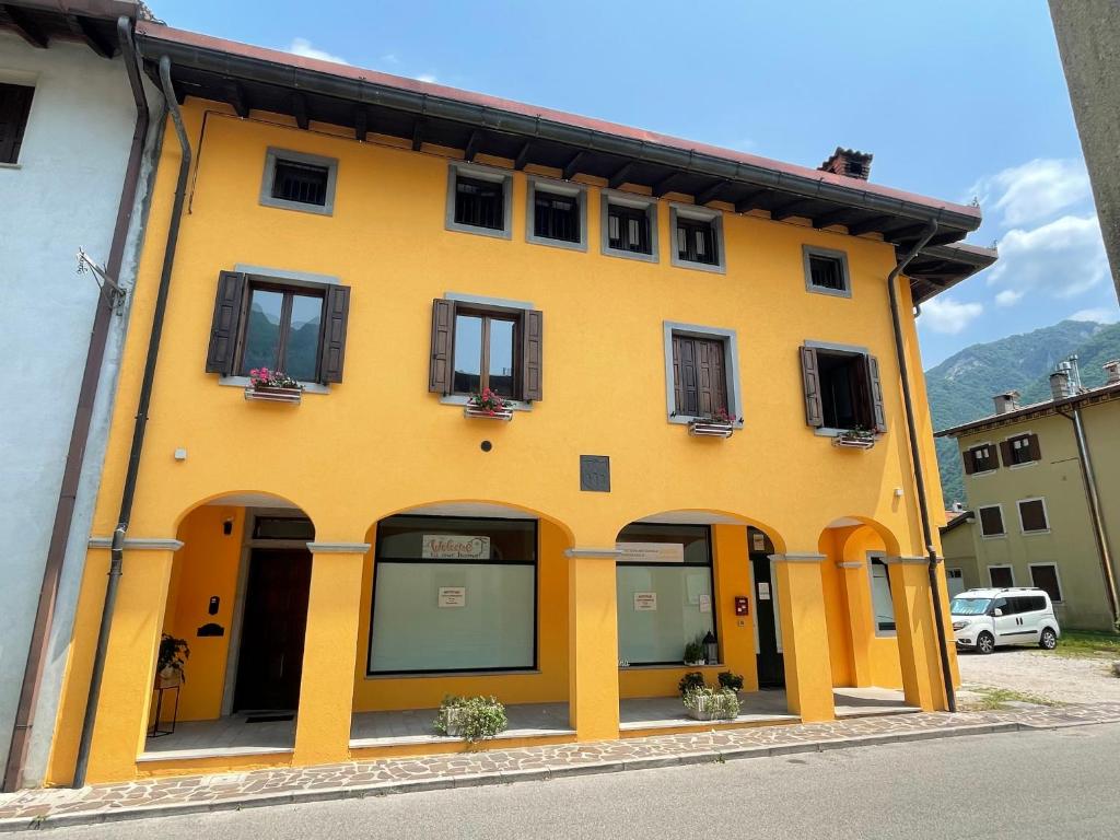 een geel gebouw met ramen aan een straat bij Al Borgo Appartamento in Venzone